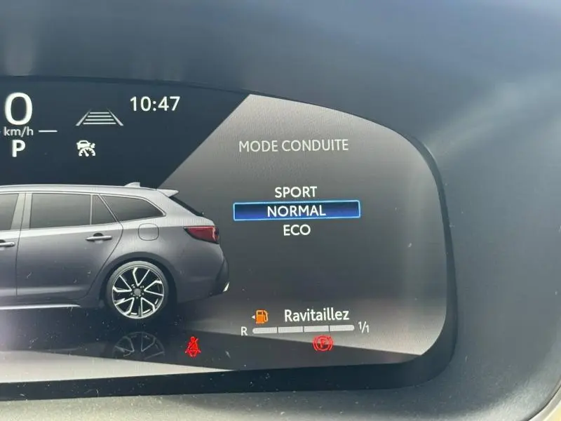 Affichage numérique intérieur montrant le mode de conduite et une voiture grise de profil côté gauche.