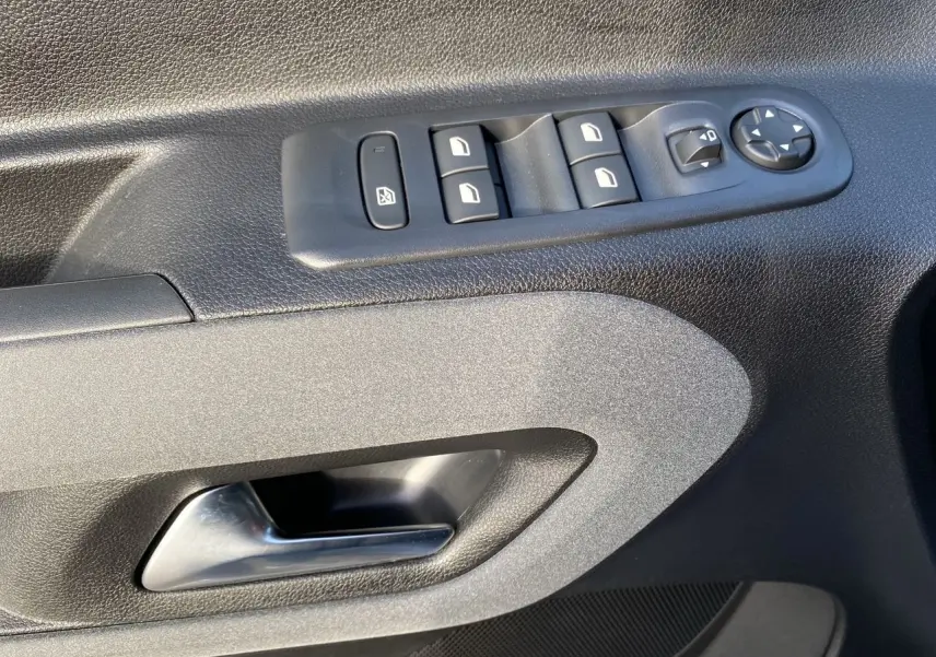 Poignée intérieure et commandes des vitres côté conducteur du Peugeot Rifter gris acier, vue rapprochée.