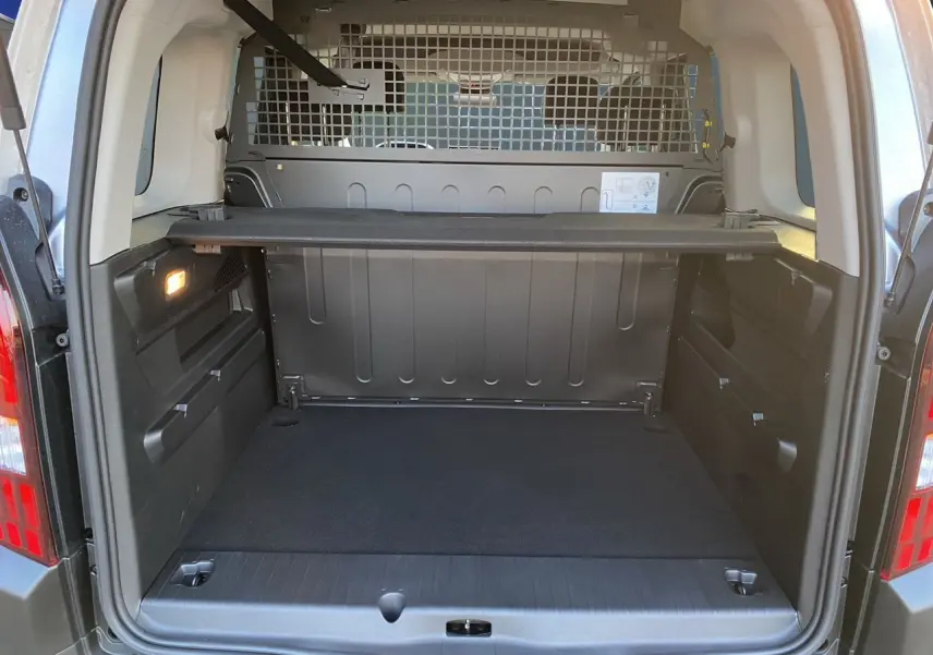 Coffre ouvert du Peugeot Rifter gris acier, vue arrière montrant la cloison métallique et le cache-bagages.