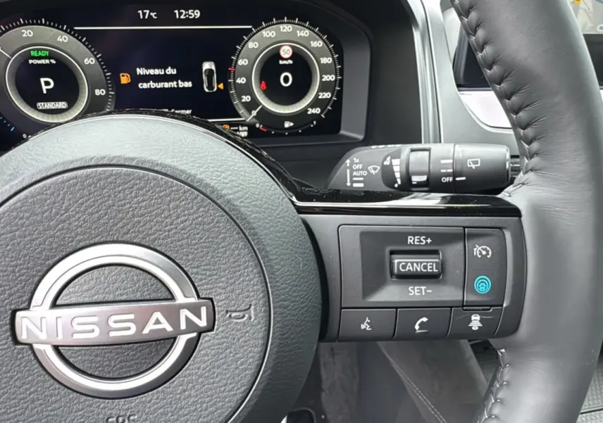 Gros plan sur le volant cuir multifonctions du Nissan Qashqai E-POWER 205 Tekna Plus avec tableau de bord numérique.