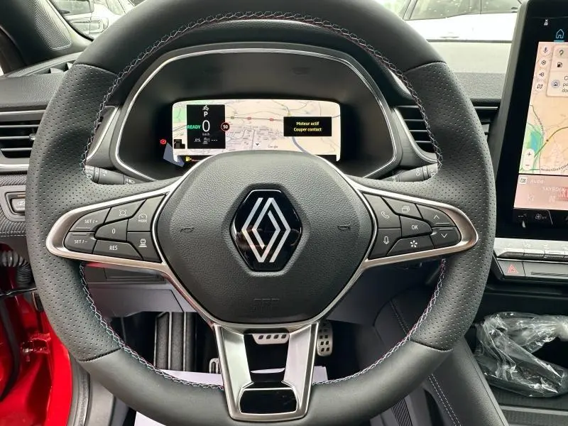 Vue rapprochée du volant perforé du Renault Captur 2025 hybride, avec logo central et commandes intégrées.