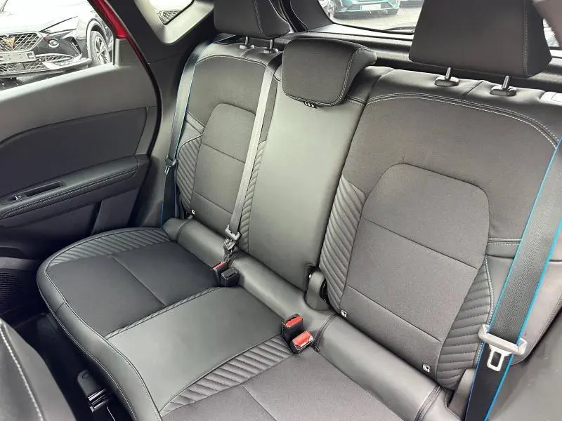 Vue intérieure arrière du Renault Captur 2025, sièges noirs avec surpiqûres bleues et ceintures assorties.