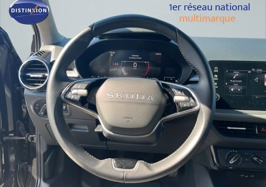 Vue intérieure centrée sur le volant noir de la Skoda Fabia 2025, avec tableau de bord numérique et écran tactile visibles.