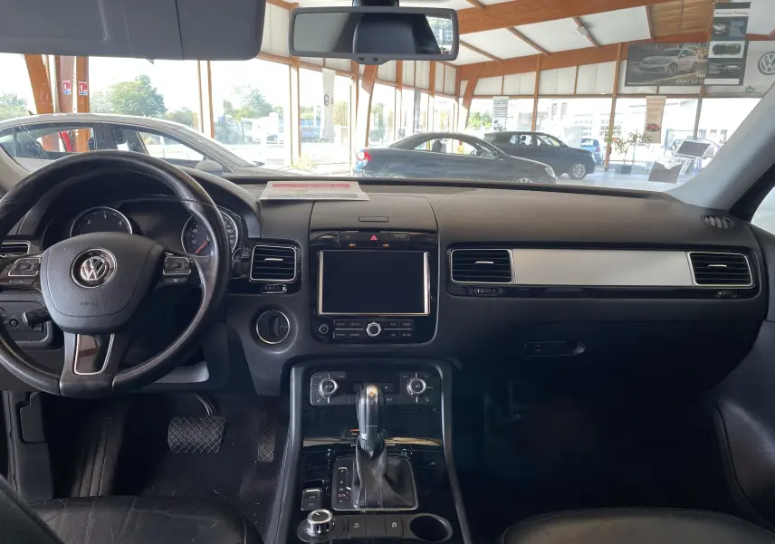 Vue intérieure du tableau de bord noir du Volkswagen Touareg 2012, avec volant multifonction et console centrale moderne.