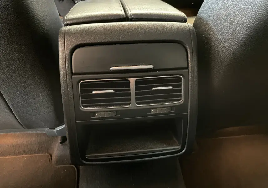 Détail des aérateurs arrière noirs et rangement central du Volkswagen Touareg 2012 finition Carat en cuir noir.