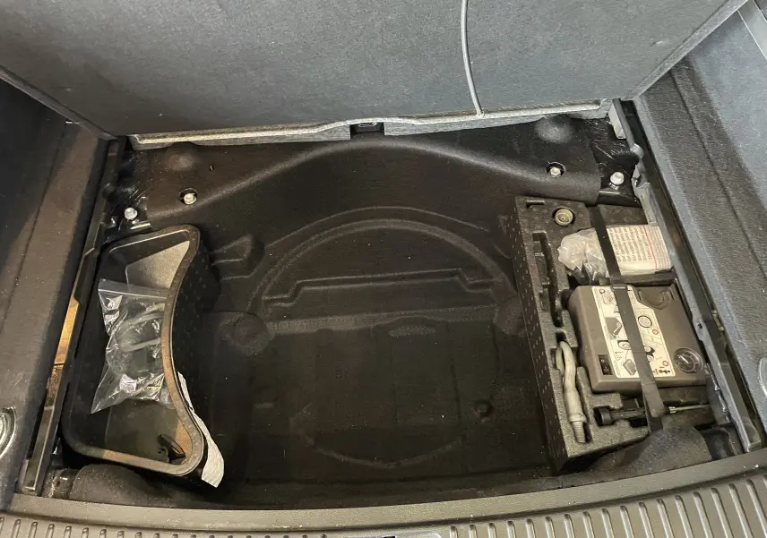 Compartiment de rangement sous le coffre du Volkswagen Touareg noir 2012, montrant le kit de réparation pneus et espace vide.