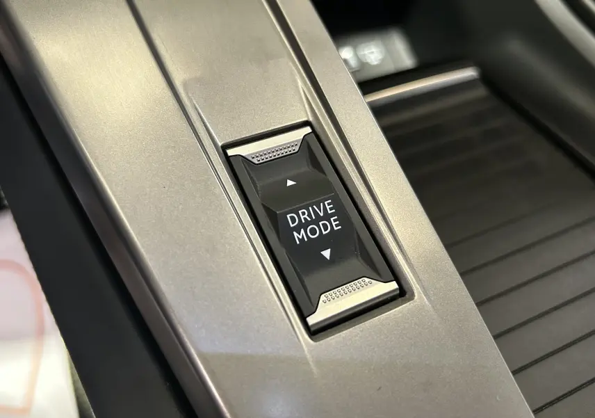 Gros plan sur le bouton Drive Mode intégré à la console centrale gris métallisé de la Peugeot 308 SW III GT 2024.