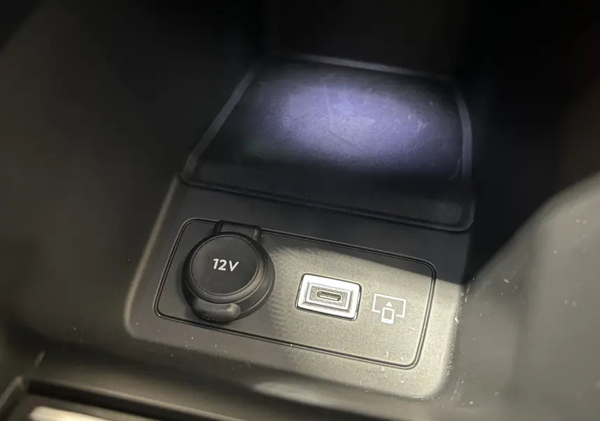 Gros plan sur la prise 12V et port USB-C du Peugeot 308 SW III GT BlueHDi 130 EAT8 gris Sellenium, intérieur noir.