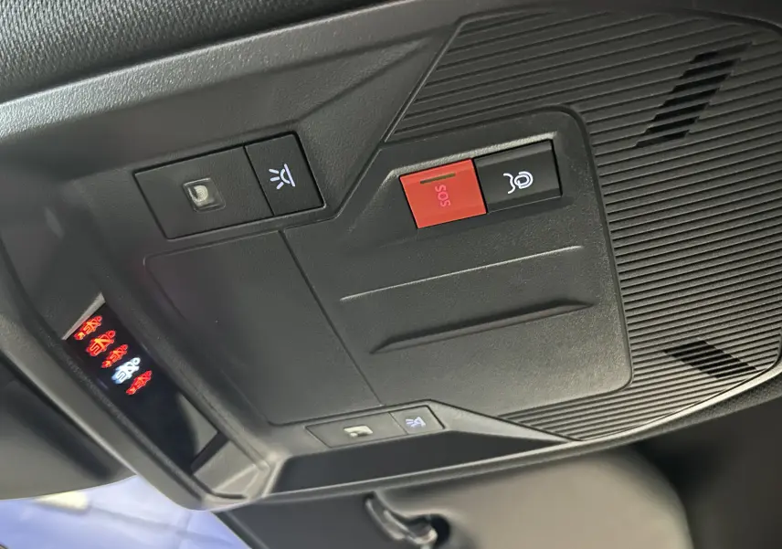 Vue rapprochée du panneau de commandes au plafond intérieur du Peugeot 308 SW 2024 gris Sellenium avec bouton SOS rouge.