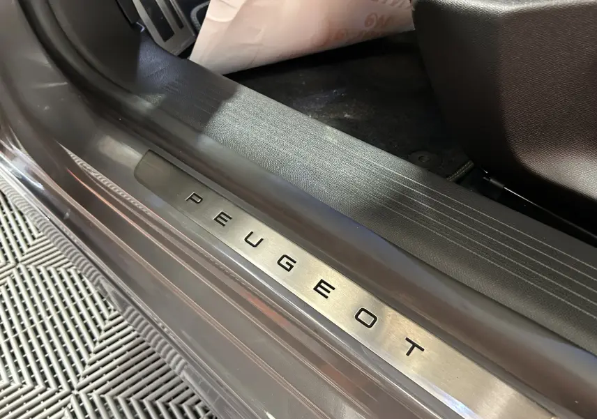 Gros plan sur la plaque de seuil de porte Peugeot en acier brossé, intérieur gris Sellenium du 308 SW 2024.