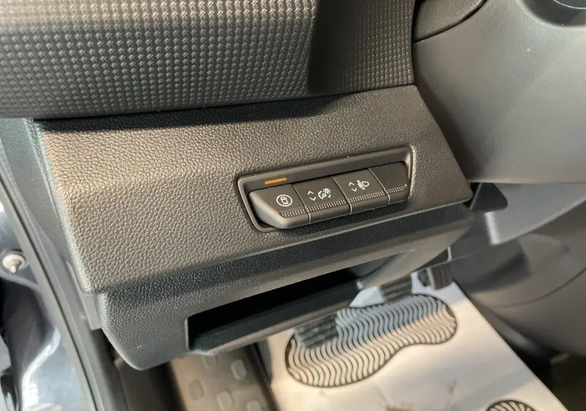 Gros plan sur les commandes d'éclairage et réglages situés sous le tableau de bord côté gauche du Renault Trafic Fourgon gris Comète.