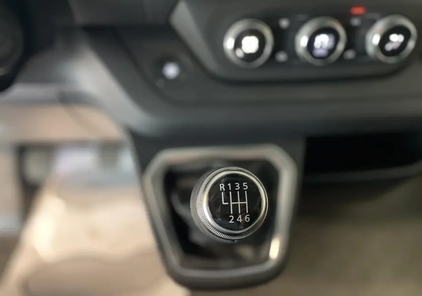 Gros plan sur le levier de vitesses manuel du Renault Trafic Fourgon L2H1, avec commandes de climatisation en arrière-plan.