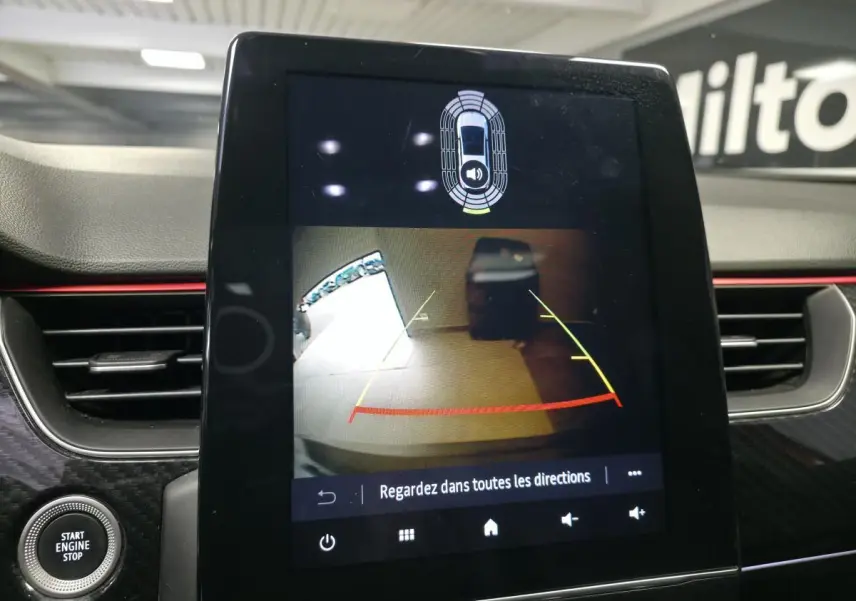 Écran tactile central montrant la caméra de recul du Renault Arkana R.S. Line, tableau de bord avec finition carbone et bandeau rouge.