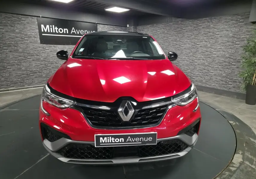 Vue frontale d'un Renault Arkana rouge flamme avec calandre noir brillant et logo Renault centré.