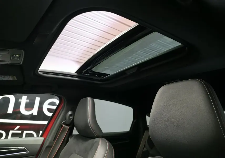 Intérieur du Renault Arkana rouge, vue sur les sièges avant en cuir noir avec surpiqûres rouges et toit ouvrant électrique.