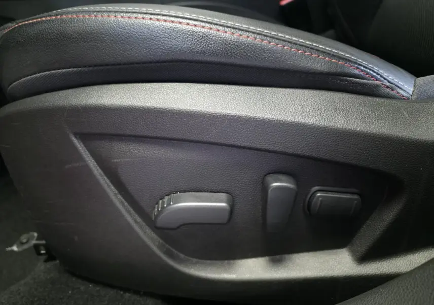 Détail des commandes électriques de réglage du siège avant avec surpiqûres rouges dans Renault Arkana Rouge Flamme 2023.