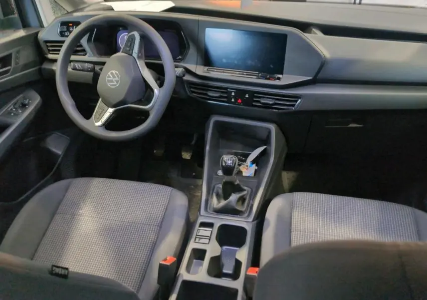 Vue intérieure avant du Volkswagen Caddy Maxi 2024, volant multifonction, tableau de bord digital et boîte manuelle.
