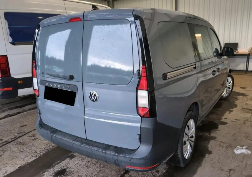 Vue 3/4 arrière droite d'un Volkswagen Caddy Maxi 2024 gris Pure Grey avec portes arrière battantes tôlées et porte latérale coulissante.