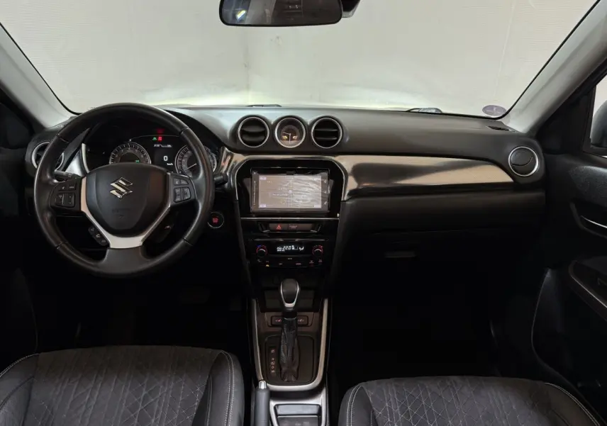 Vue intérieure frontale du tableau de bord noir du Suzuki Vitara 1.5 Dualjet hybrid STYLE avec volant cuir alu multifonctions.