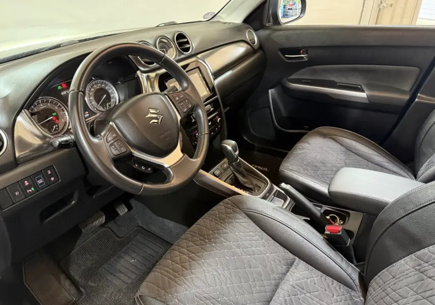 Vue intérieure côté conducteur du Suzuki Vitara noir 2022 avec volant cuir alu multifonctions et console centrale automatique.