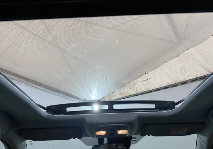 Vue intérieure du toit ouvrant électrique en verre du Suzuki Vitara noir 2022, avec éclairage intérieur allumé.