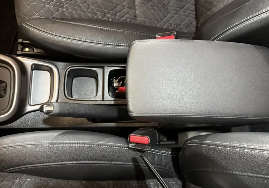 Vue plongeante sur la console centrale noire du Suzuki Vitara 2022, avec frein à main manuel et accoudoir cuir.