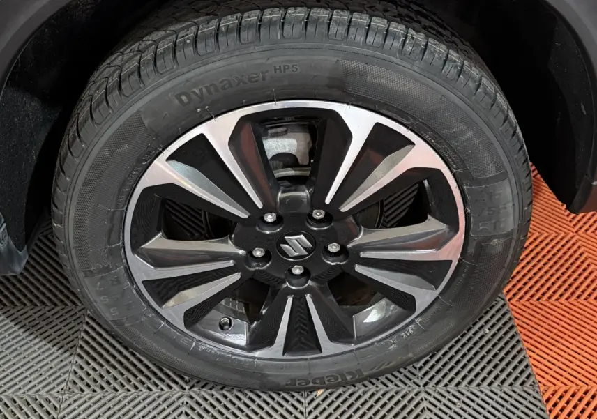 Gros plan sur la roue avant droite du Suzuki Vitara noir, mettant en valeur la jante alliage bicolore au design moderne.