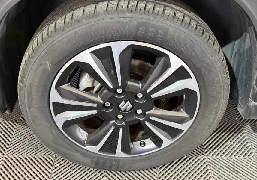Gros plan sur la roue avant droite du Suzuki Vitara noir, mettant en valeur la jante alliage bicolore au design moderne.