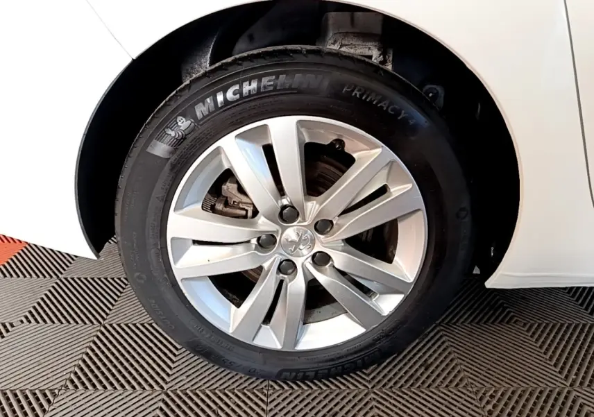 Vue rapprochée de l'aile arrière droite d'une Peugeot 308 blanche, mettant en valeur la roue et le passage de roue.