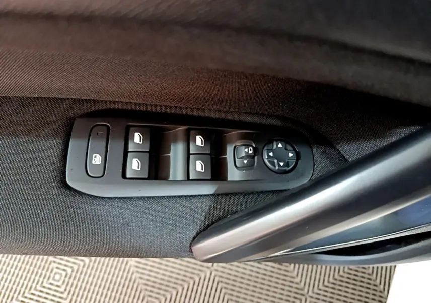 Détail des commandes des vitres et rétroviseurs sur la porte côté conducteur d’une Peugeot 308 blanche 2021.