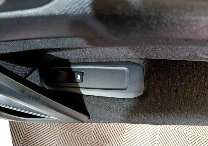 Détail de la commande d'ouverture intérieure de porte sur la PEUGEOT 308 blanche, vue rapprochée du panneau noir.