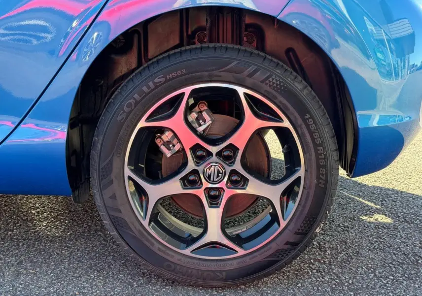 Gros plan sur la roue avant gauche de la MG3 1.5 Hybrid+ 195ch Comfort en Como Blue métallisé avec jante alu distinctive.
