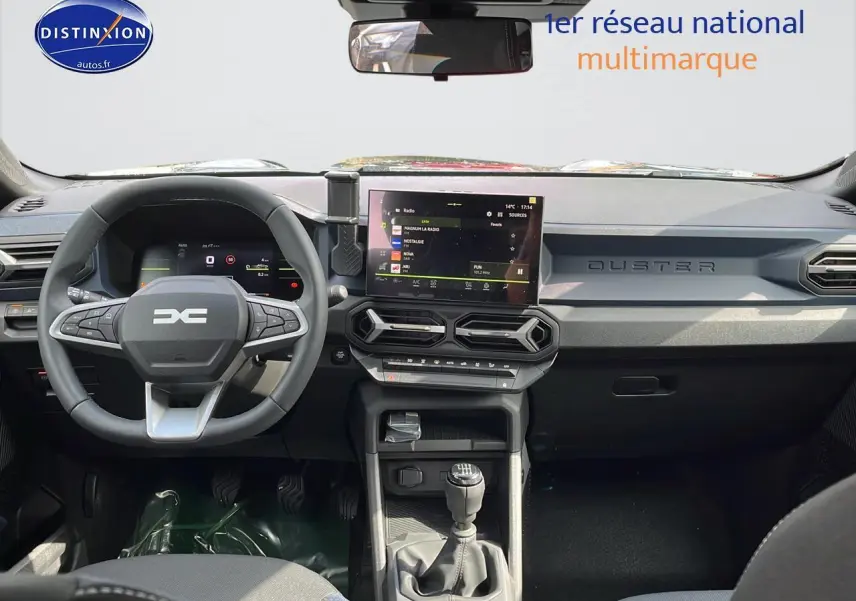 Tableau de bord et volant multifonction du Dacia Duster gris schiste 2025 vus de face, avec écran tactile central.