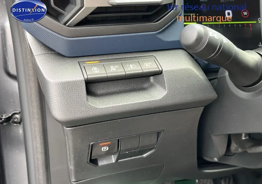 Détail du tableau de bord côté gauche du Dacia Duster gris schiste 2025 avec commandes d'aide à la conduite et frein à main électrique.