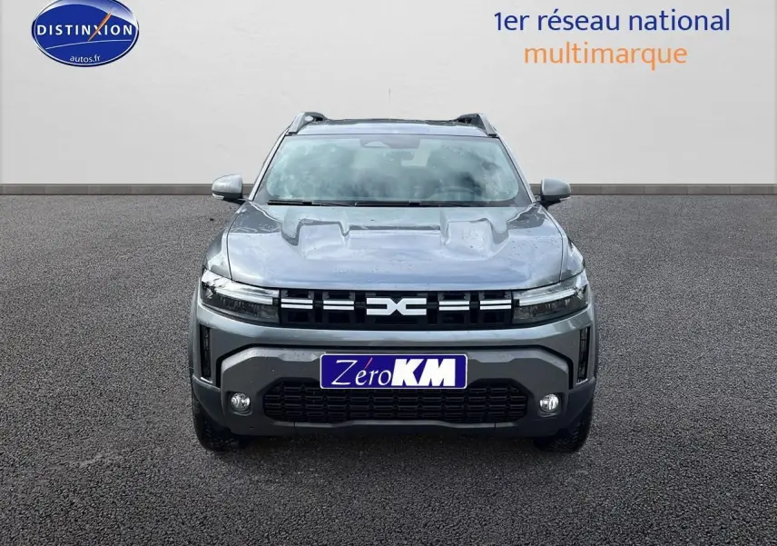 Vue avant du Dacia Duster 2025 gris schiste avec calandre distinctive et phares LED fins allumés.