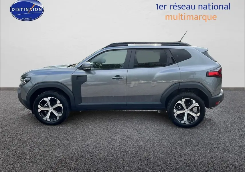 Profil droit du Dacia Duster gris schiste 2025 avec barres de toit et jantes alu distinctives.