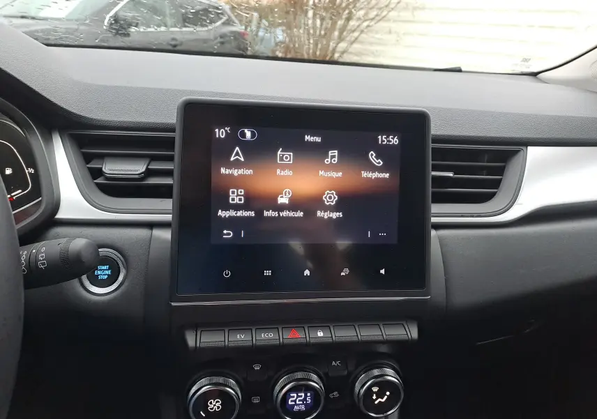 Vue rapprochée de l’écran tactile central et de la console du Renault Captur gris cassiopée, avec commandes climatisation et bouton start/stop.
