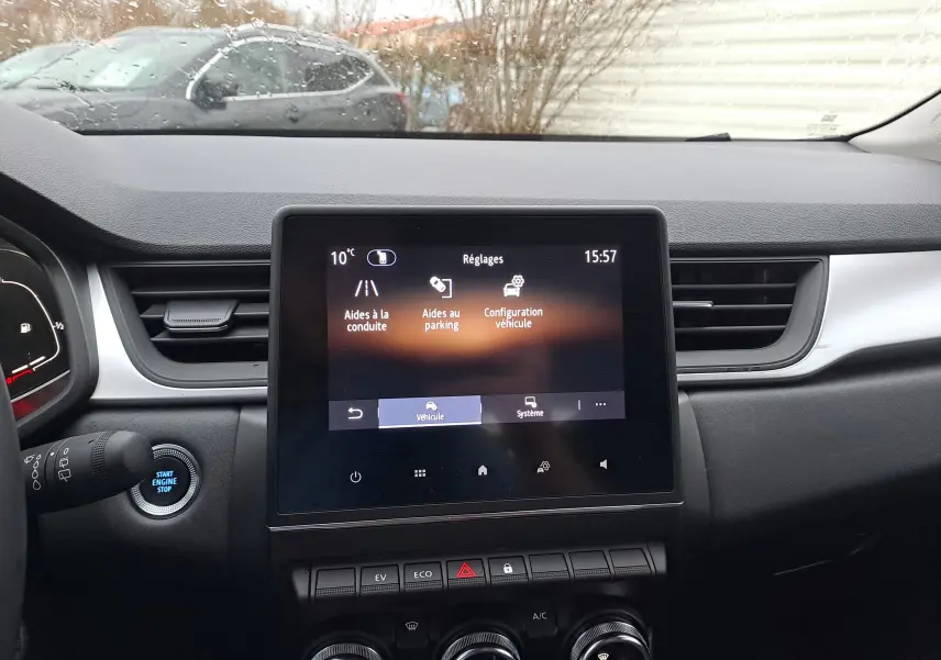 Vue intérieure du tableau de bord du Renault Captur gris cassiopée, avec écran tactile central affichant les réglages du véhicule.