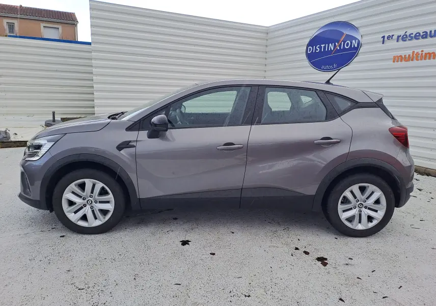 Profil côté gauche d'un Renault Captur gris cassiopée métal 2022, avec jantes alliage et lignes sculptées visibles.