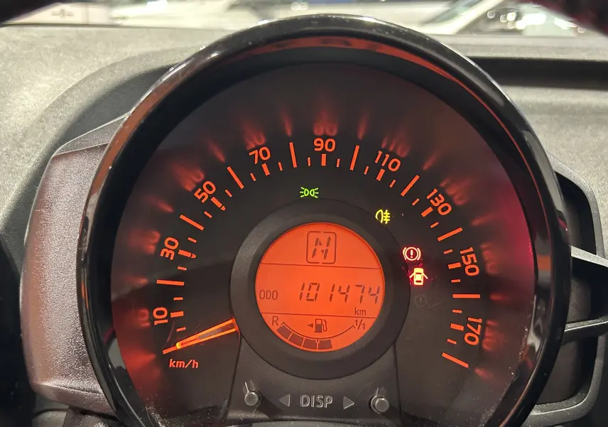 Vue rapprochée du compteur de vitesse rouge éclairé d'une Citroën C1, affichant 101474 km au compteur.