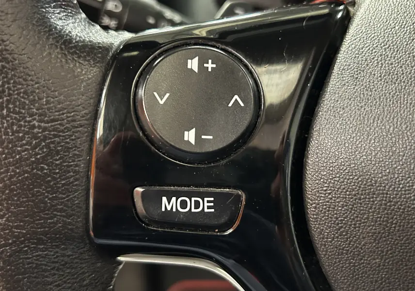 Gros plan sur les commandes de volume et mode sur le volant noir de la Citroën C1 Airscape rouge de 2019.