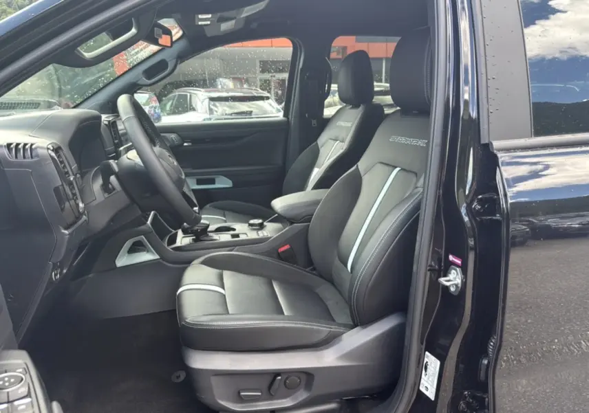 Intérieur du Ford Ranger 2025 noir agate, vue côté conducteur ouverte, sièges Stormtrak avec surpiqûres blanches visibles.