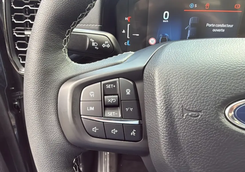 Gros plan sur le volant côté gauche du Ford Ranger 2025 noir agate, avec commandes de régulateur et affichage numérique.