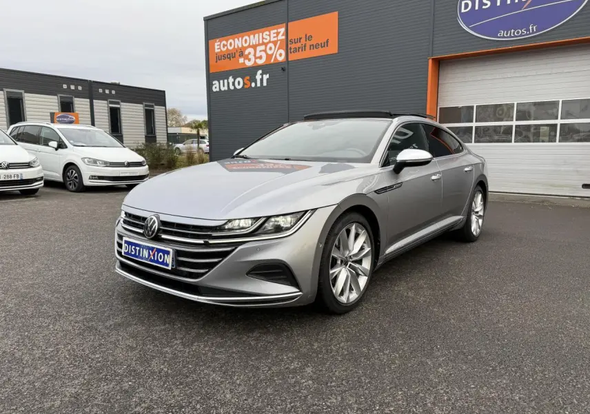 Volkswagen Arteon gris pyrite métallisé vue 3/4 avant droit avec jantes alliage 19 pouces devant un garage autos.fr