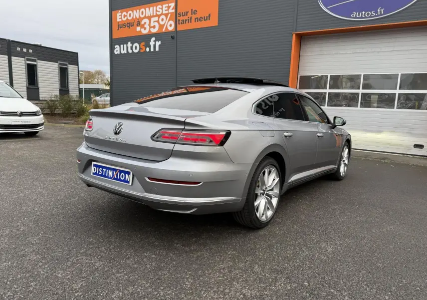 Vue 3/4 arrière droite d'une Volkswagen Arteon gris pyrite métallisé avec jantes alliage 19 pouces devant un garage.