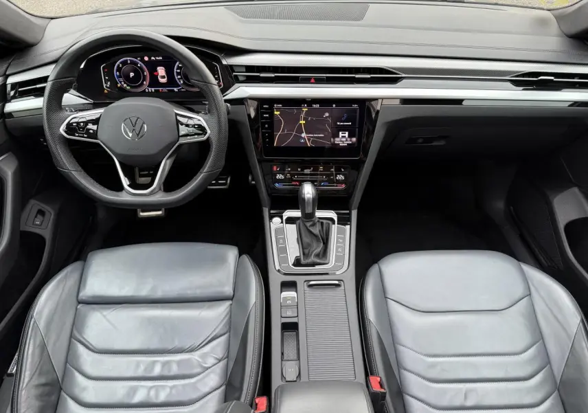 Vue intérieure frontale du tableau de bord et des sièges en cuir gris d'une Volkswagen Arteon 2021 avec écran tactile central.
