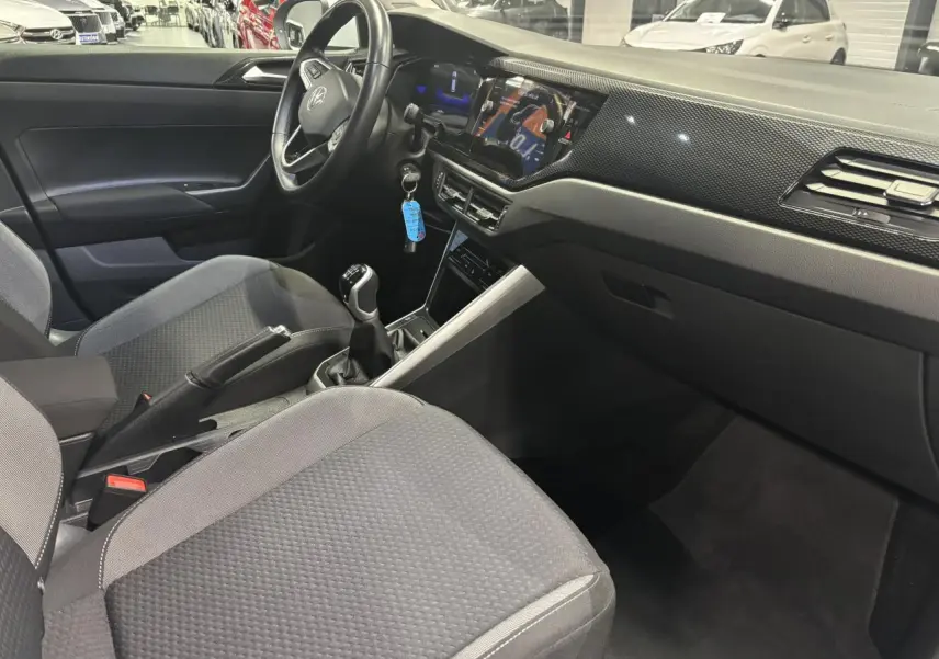 Vue intérieure côté conducteur du Volkswagen Taigo 2023 avec tableau de bord noir et volant cuir multifonctions.