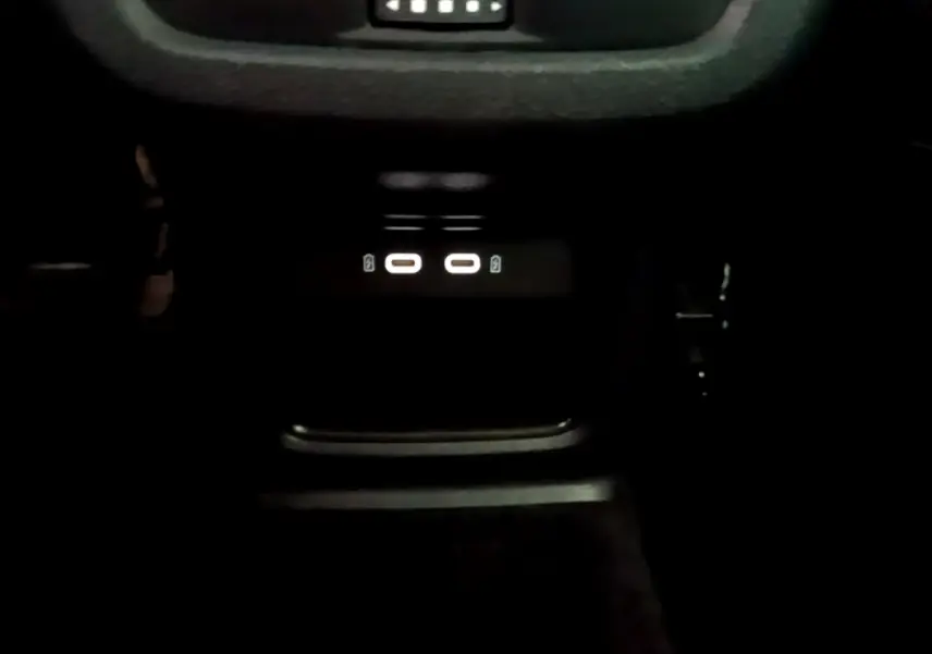 Gros plan sur la zone de recharge par induction avec ports USB-C éclairés dans l'habitacle sombre du SEAT Ateca gris.