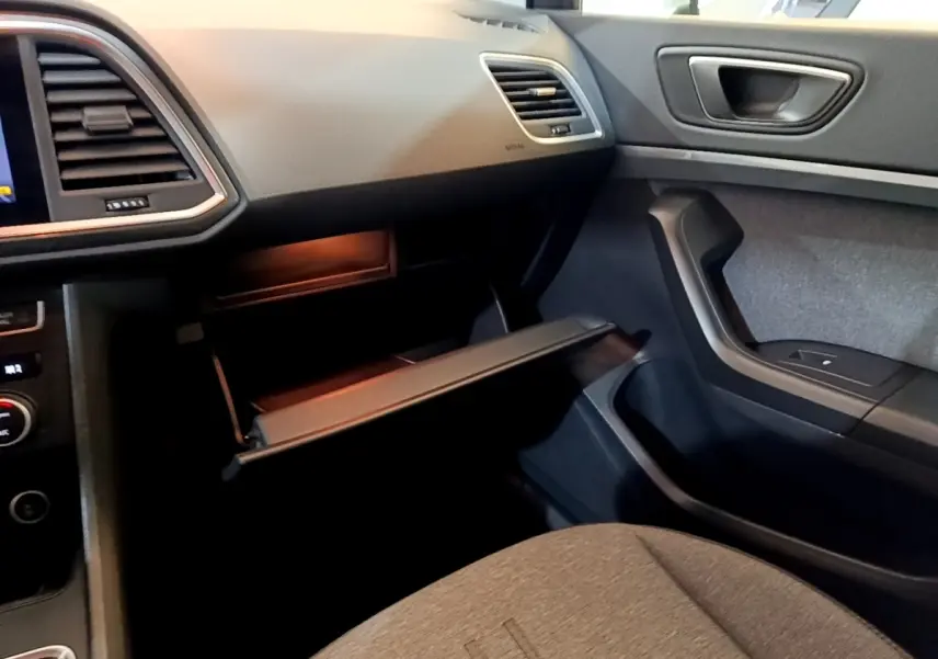 Vue intérieure côté passager du tableau de bord gris clair et boîte à gants ouverte du SEAT Ateca 2022.