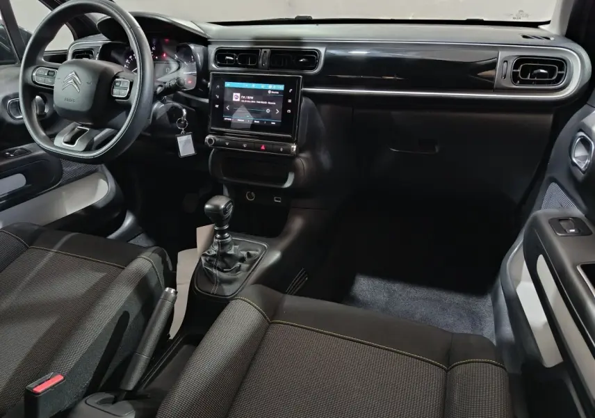 Intérieur avant droit de la Citroën C3 2024 gris foncé, volant multifonctions, écran tactile central et boîte manuelle.